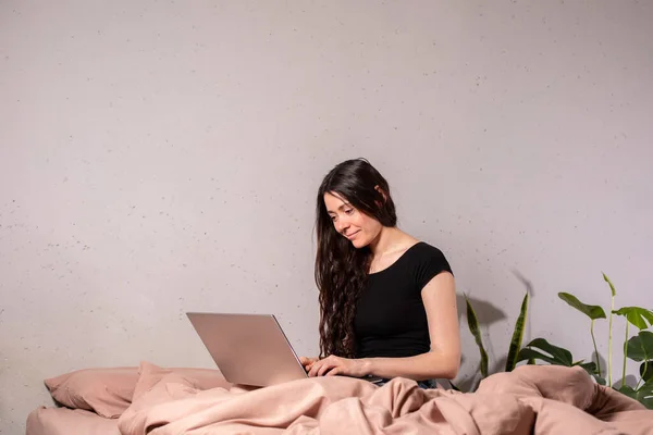 The concept of social distance and isolation. Work from home remotely over the Internet. A young woman works at home on a computer.