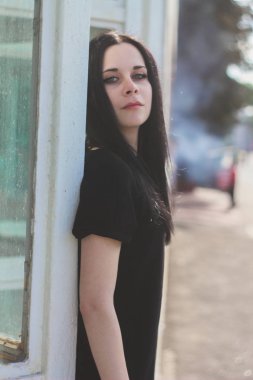 Kısacası küçük elbise mavi cam arka plan üzerinde siyah poz genç sıska çekici güzel ve seksi esmer kadın hanım. soğuk renkler, yüksek moda