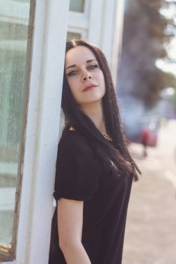 Kısacası küçük elbise mavi cam arka plan üzerinde siyah poz genç sıska çekici güzel ve seksi esmer kadın hanım. soğuk renkler, yüksek moda