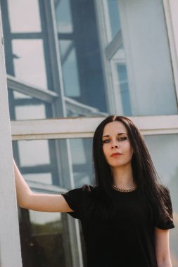 Kısacası küçük elbise mavi cam arka plan üzerinde siyah poz genç sıska çekici güzel ve seksi esmer kadın hanım. soğuk renkler, yüksek moda