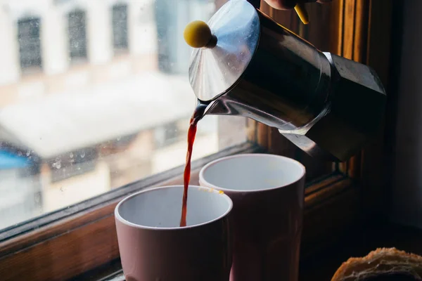 Mokka-Kanne und Kaffee einschenken. Nahaufnahme von Hand tropft Kaffee Stockfoto