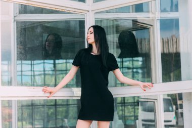 Genç sıska kısa poz güzel ve seksi esmer Gotik Bayan büyüleyici bir alışveriş arka plan üzerinde siyah elbise