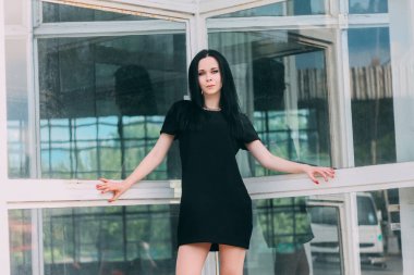 Genç sıska kısa poz güzel ve seksi esmer Gotik Bayan büyüleyici bir alışveriş arka plan üzerinde siyah elbise