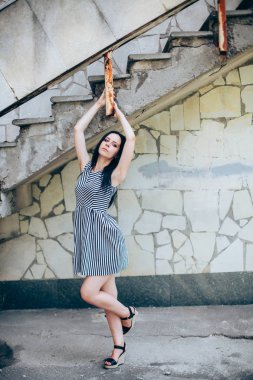 Genç sıska kısa elbise siyah ve beyaz çizgili poz Bayan büyüleyici. güzel ve seksi esmer gösteren moda poz terk edilmiş binalar arka plan üzerinde