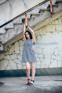 Genç sıska kısa elbise siyah ve beyaz çizgili poz Bayan büyüleyici. güzel ve seksi esmer gösteren moda poz terk edilmiş binalar arka plan üzerinde