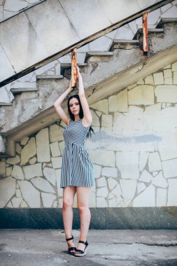 Genç sıska kısa elbise siyah ve beyaz çizgili poz Bayan büyüleyici. güzel ve seksi esmer gösteren moda poz terk edilmiş binalar arka plan üzerinde