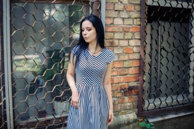 Genç sıska kısa elbise siyah ve beyaz çizgili poz Bayan büyüleyici. güzel ve seksi esmer gösteren moda poz terk edilmiş binalar arka plan üzerinde