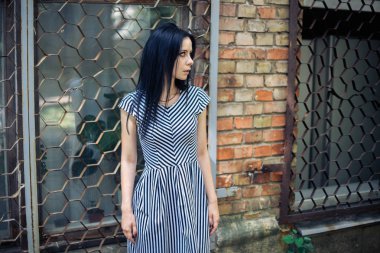 Genç sıska kısa elbise siyah ve beyaz çizgili poz Bayan büyüleyici. güzel ve seksi esmer gösteren moda poz terk edilmiş binalar arka plan üzerinde