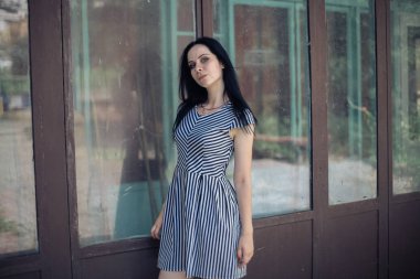 Genç sıska kısa elbise siyah ve beyaz çizgili poz Bayan büyüleyici. güzel ve seksi esmer gösteren moda poz terk edilmiş binalar arka plan üzerinde