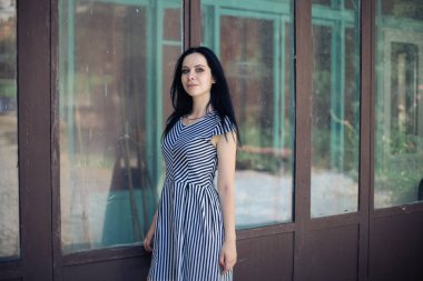 Genç sıska kısa elbise siyah ve beyaz çizgili poz Bayan büyüleyici. güzel ve seksi esmer gösteren moda poz terk edilmiş binalar arka plan üzerinde