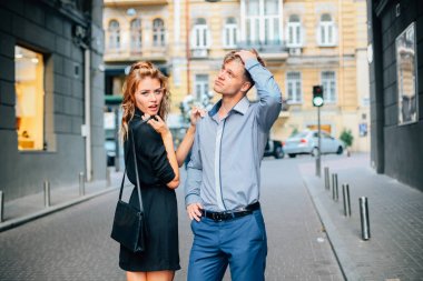 sevimli ve komik bir çift erkek ve kadın sarışın kapalı kameraya poz ve şehrin arka plan üzerinde gülümseyen