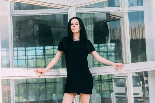 Junge dünne charmante schöne und sexy brünette Gothic Lady posiert in kurzem Kleid schwarz auf einem Mall-Hintergrund — Stockfoto