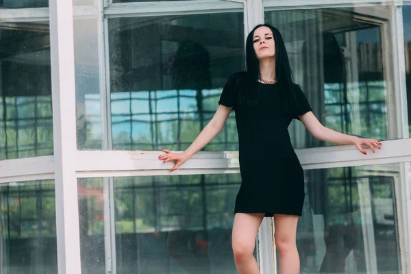 young skinny charming nice and sexy brunette gothic lady posing in short dress black on a mall background