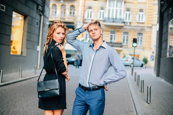 cute and funny couple man and woman blond Caucasians posing at the camera and smiling on the background of the city
