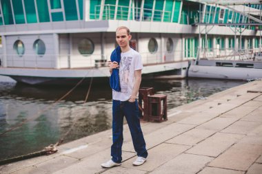 Çekici bir genç adam rahat bakmak nehir kenarında yürüyüş ile kentsel ve modern arka plan