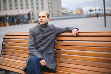 bıkkın ve meşgul yalnız genç bekar adam 30 bir gri bir parkta bankta oturan your love için bekliyor ceket