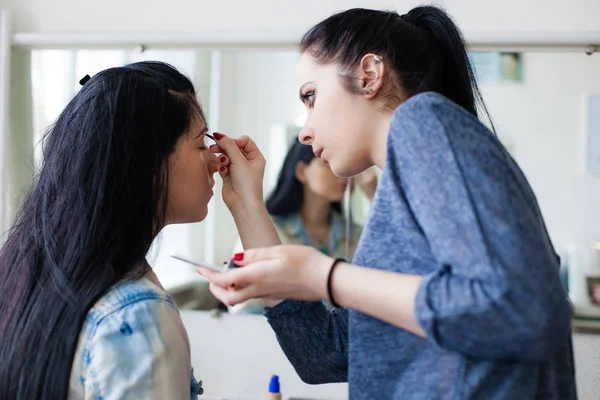 Backstage scen: professionell Make-up artist gör glamour modell makeup vid arbete nära spegeln — Stockfoto