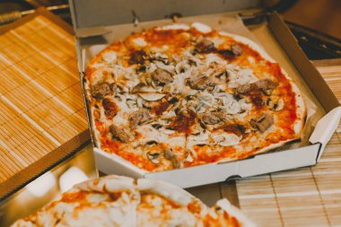 Tablo üzerinde iki lezzetli sıcak dilimlenmiş pizza Salam ile rustik pizza, kopya alanı ile mozzarella fesleğen üst görünümü. Domates ve zeytin ile cam masada iki pizza