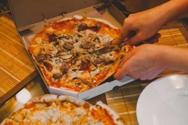 Genç kadının el tablo lezzetli sıcak dilim içine pizza Cuts Salam ile rustik pizza, kopya alanı ile mozzarella fesleğen üst görünümü. Domates ve zeytin ile cam masada iki pizza