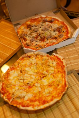 Tablo üzerinde iki lezzetli sıcak dilimlenmiş pizza Salam ile rustik pizza, kopya alanı ile mozzarella fesleğen üst görünümü. Domates ve zeytin ile cam masada iki pizza