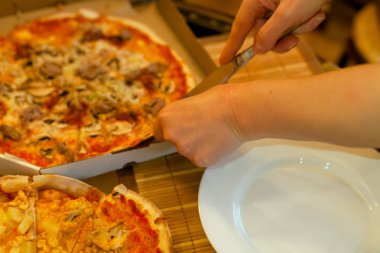 Genç kadının el tablo lezzetli sıcak dilim içine pizza Cuts Salam ile rustik pizza, kopya alanı ile mozzarella fesleğen üst görünümü. Domates ve zeytin ile cam masada iki pizza