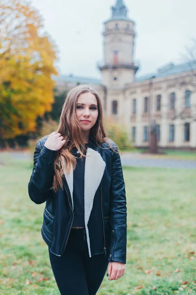 Portrait fashion of a beautiful blonde young caucasian woman In a black fur jacket cold Autumn getaways spring. posing next to the tower — Stock Photo, Image