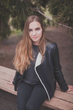 Güzel sarışın genç bir beyaz kadın siyah kürk ceket soğuk Sonbahar Bahar portresi. sonbahar parkta bankta oturmuş portre, vintage Krem sarı renk,