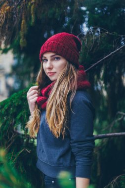 Güzel sarışın genç Kafkas kadın hipster moda köknar dallarında poz siyah kürk ceket portresi. Bordo kap ve eşarp. gülen saadettir gülümseyen