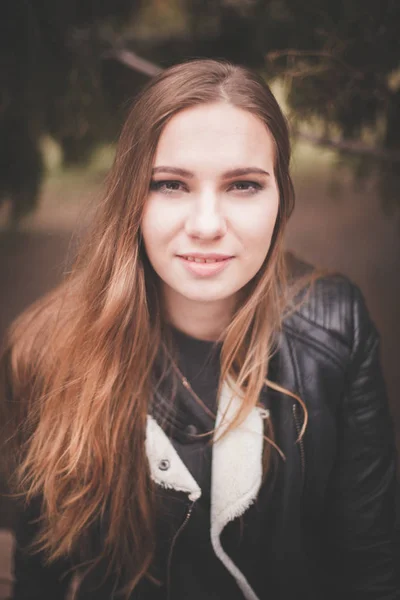 Porträt einer schönen blonden jungen kaukasischen Frau in einer schwarzen Pelzjacke kalten Herbstfrühling. Nahaufnahme, Vintage cremegelb, sitzt auf der Bank im Herbstpark — Stockfoto