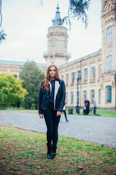 Módní portrét krásné blond mladé kavkazské ženy v černém kožešiny bunda studené podzimní pobyty jaro. pózuje vedle věže — Stock fotografie