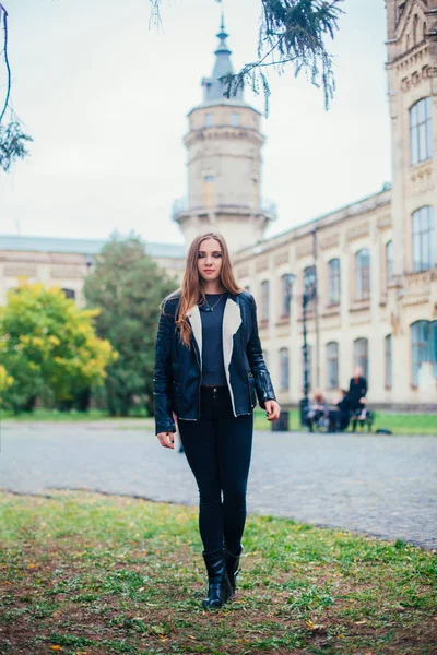 Módní portrét krásné blond mladé kavkazské ženy v černém kožešiny bunda studené podzimní pobyty jaro. pózuje vedle věže — Stock fotografie