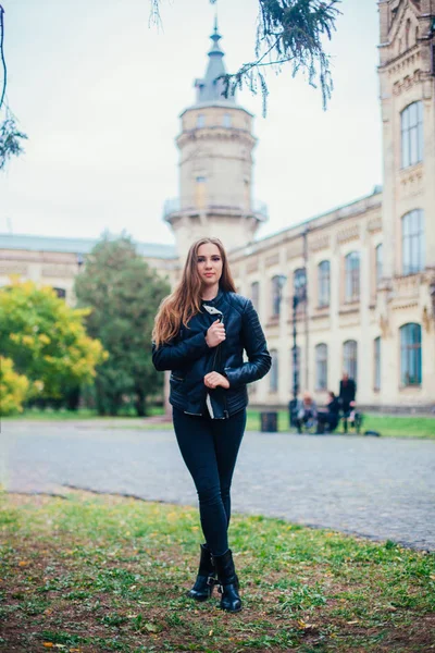 Porträtt mode av en vacker blond ung kaukasisk kvinna i en svart päls jacka kalla höst getaways våren. poserar bredvid tornet — Stockfoto
