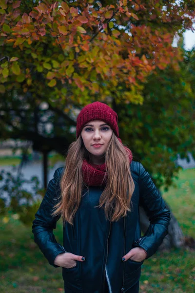 Portrait mode d'une belle blonde jeune femme caucasienne froid Escapades d'automne printemps. parc d'automne, rouge vert jaune trois. Dans une casquette bordeaux et une écharpe. Embarrassé, Dreamy belle fille — Photo