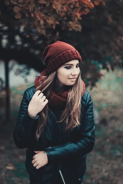 Portrait-Mode einer schönen blonden jungen kaukasischen Frau kalten Herbst Kurzurlaube Frühling. Herbstpark, rot grün gelb dreier. in weinroter Mütze und Schal. peinlich, verträumt schönes Mädchen — Stockfoto