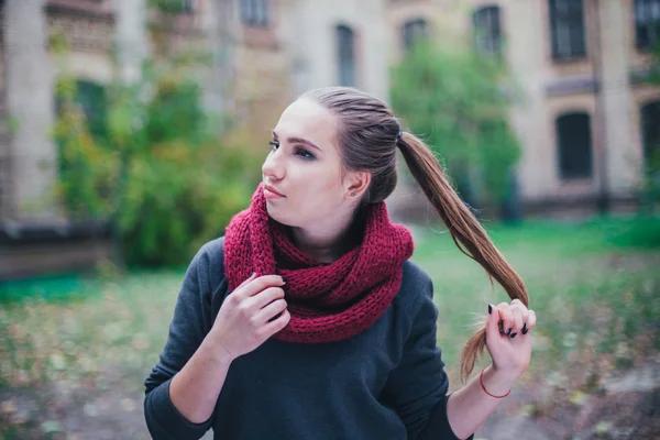 Porträtt mode på en vacker blond ung kaukasisk kvinna kalla hösten getaways våren. hösten park, röd grön gul treor. I en vinröd mössa och halsduk. Generad, drömmande vacker flicka — Stockfoto