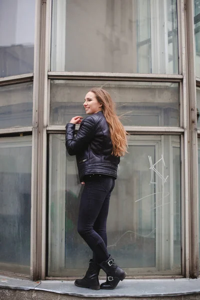 Портрет красивой блондинки молодой кавказской женщины-хипстера в черной меховой куртке, позирующей в моде рядом с голубым стеклянным зданием. городской портрет — стоковое фото