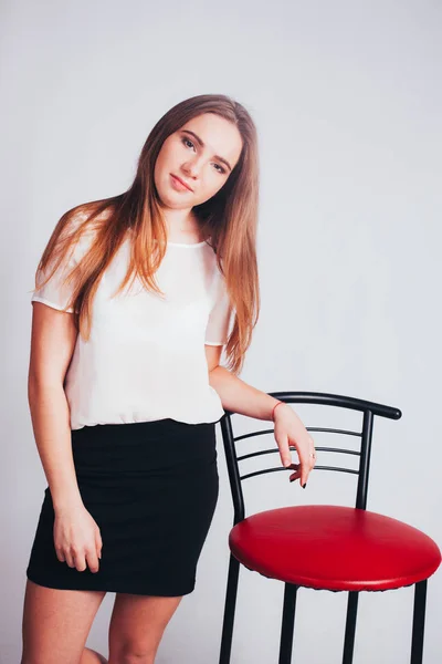studio portrait of beautiful thin blonde caucasian young woman teen girl, spring mood, isolated on white background posing in a thin blouse and short black skirt, office look, high fashion