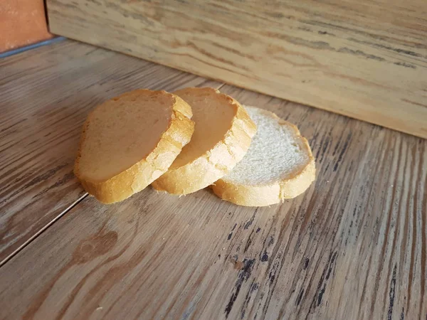Drie stukjes vers en smakelijk stokbrood op houten plank — Stockfoto