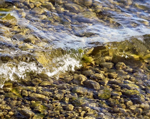 Pequeñas olas de aguas cristalinas del lago moviéndose sobre el fondo rocoso —  Fotos de Stock