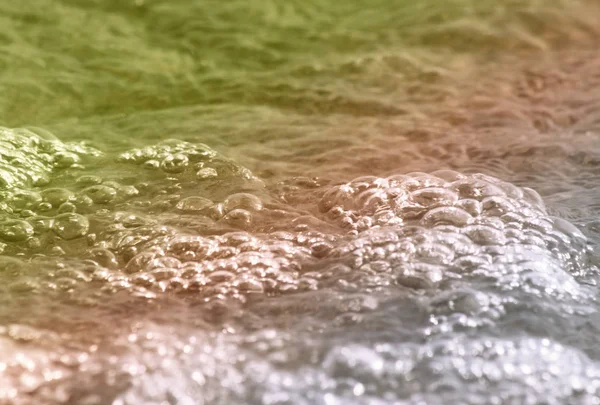 Water with soft bubbles rolling onto shore — Stock Photo, Image
