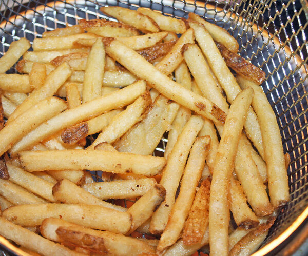 Crispy golden french fries in a deep fryer basket