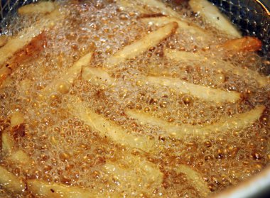 Patates kızartması yemek ve bir fritöz köpüren yağ dolu