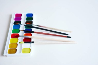 Boya fırçaları ve boyalar bir beyaz kağıt üzerinde bir dizi