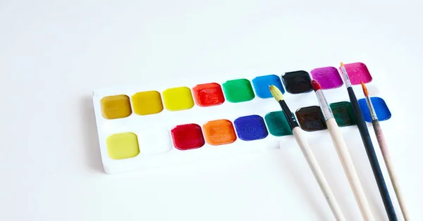 Paint brushes and a set of paints on a white paper — Stock Photo, Image