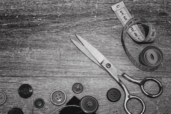 Scissors and buttons on a wooden background black white — Stock Photo, Image