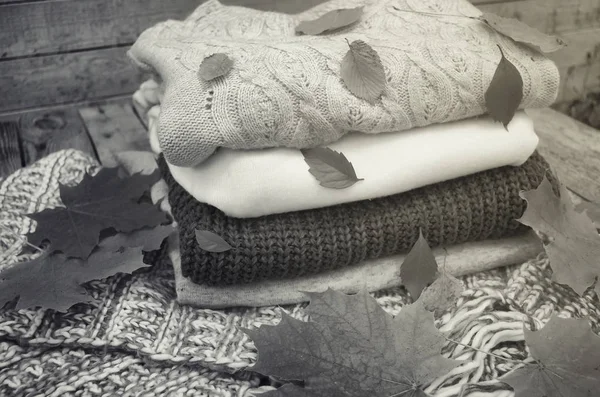 Вязаные свитера и листья на деревянном фоне — стоковое фото