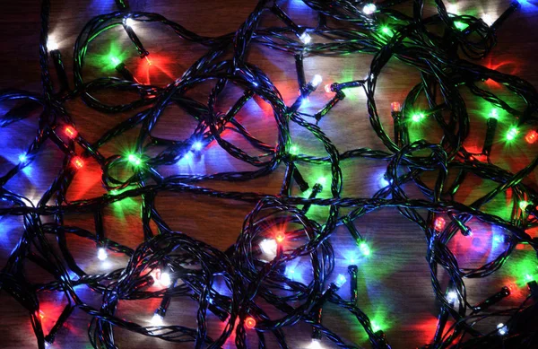 New-year electric garland on a wooden background. Bright bulbs o — Stock Photo, Image