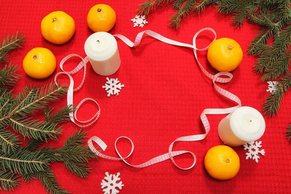 Brinquedos de árvore de Natal em um guardanapo vermelho. Mandarins e velas no th — Fotografia de Stock