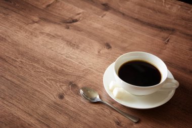 Ahşap masa bir fincan kahve ve bir kitap nesnelerde