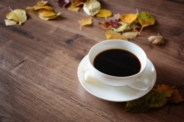 Ahşap masa bir fincan kahve ve bir kitap nesnelerde